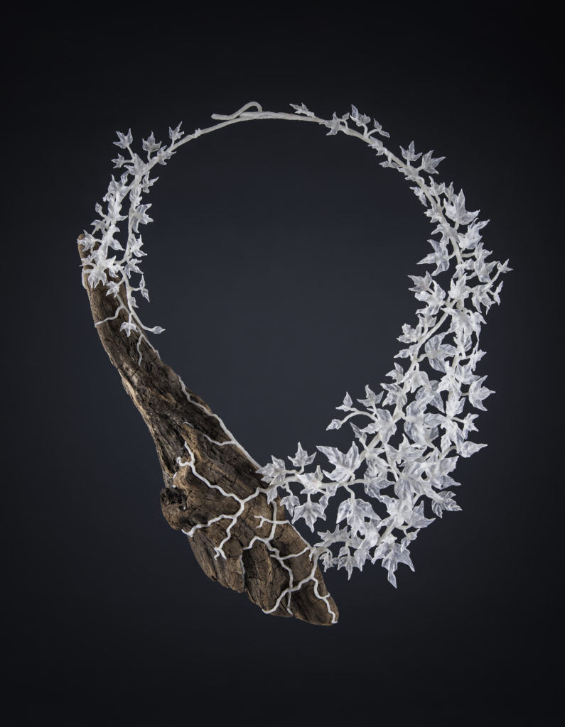 Necklace from the Hedera series. Made from plastic bags and wood. Photographed on a dark background
