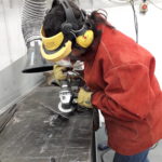 Natasha in an orange boiler suit in the workshop